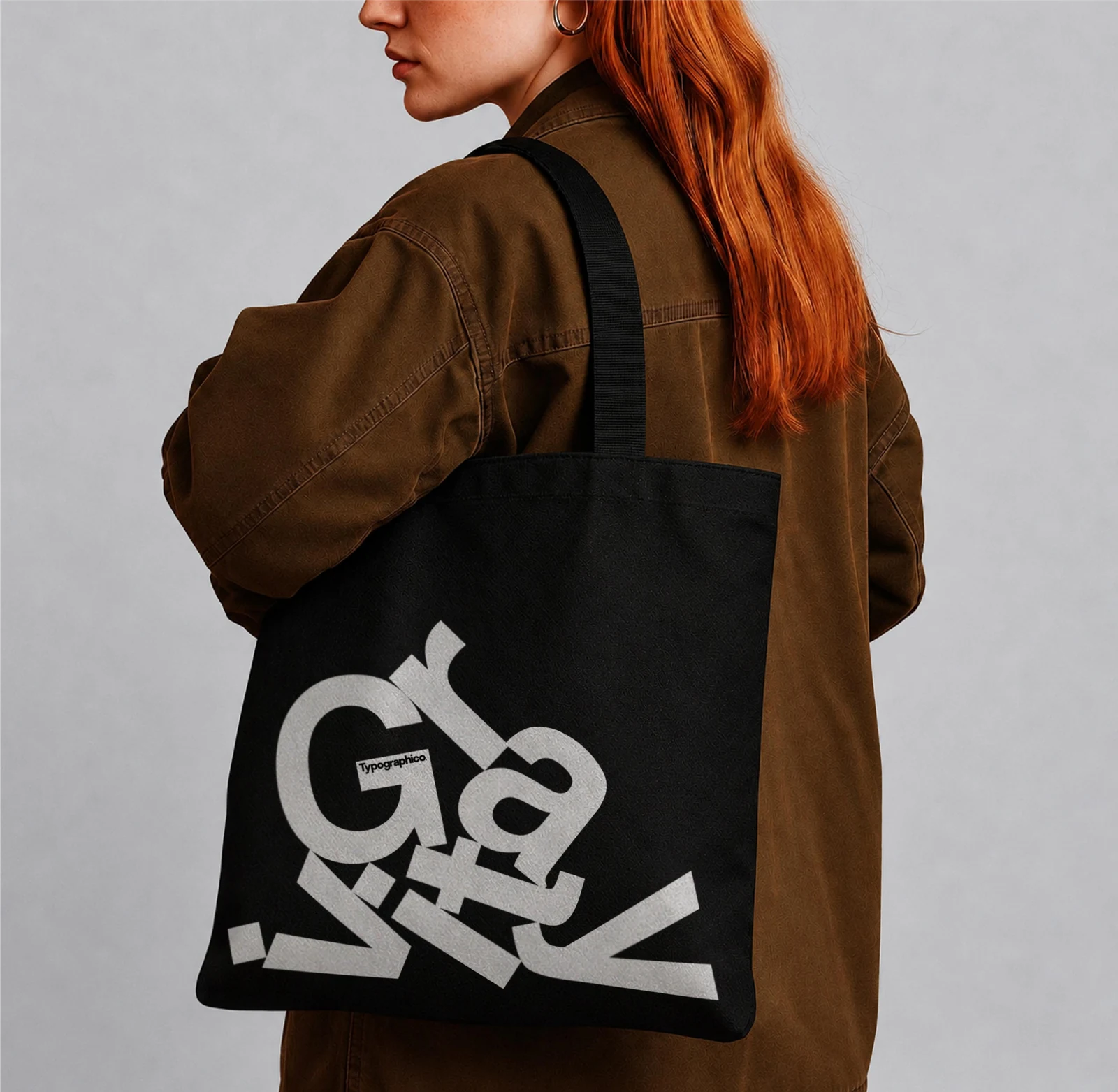 Black Gravity tote bag worn over the shoulder with a brown jacket.
