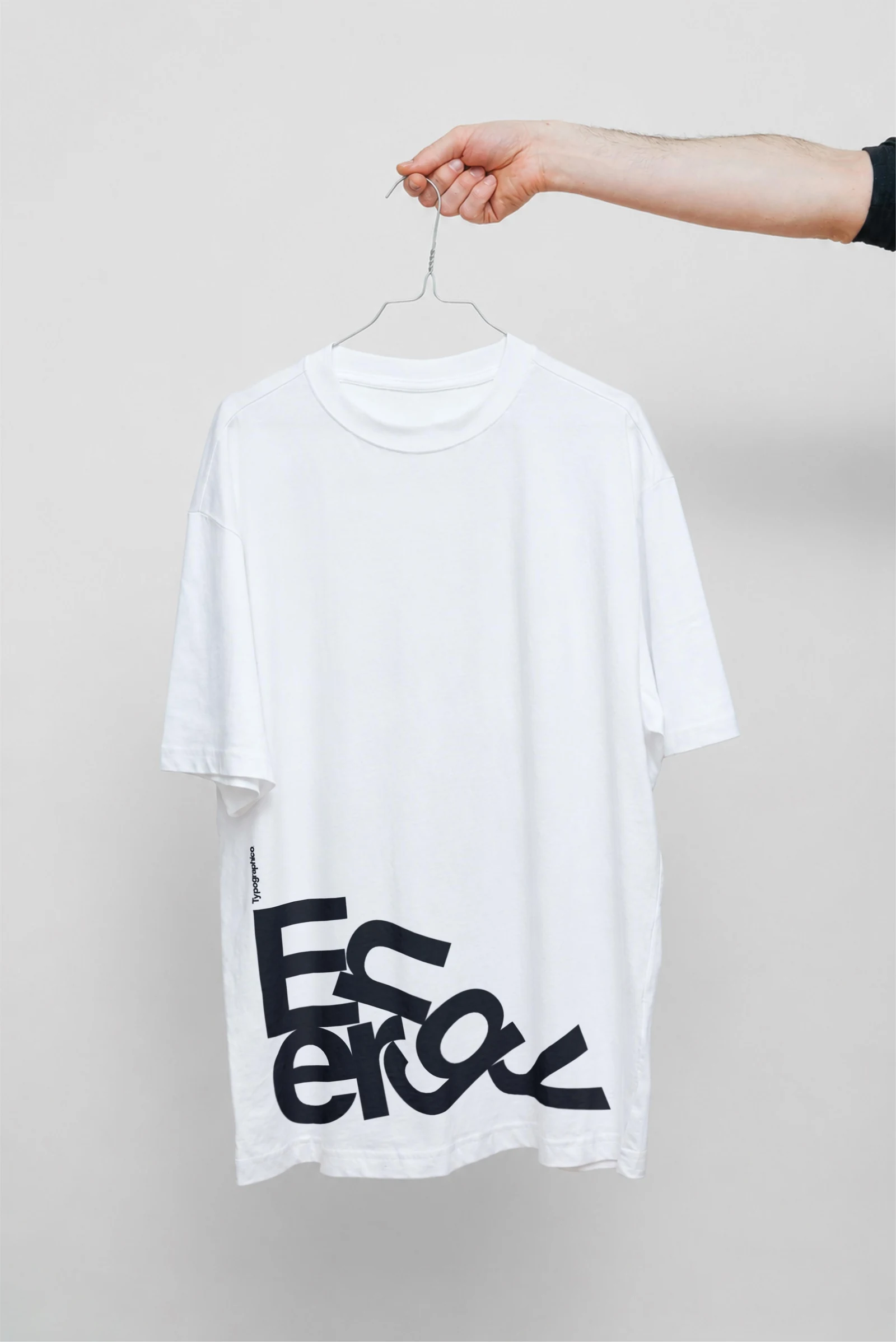 White Energy T-shirt held on a hanger against a light grey wall.