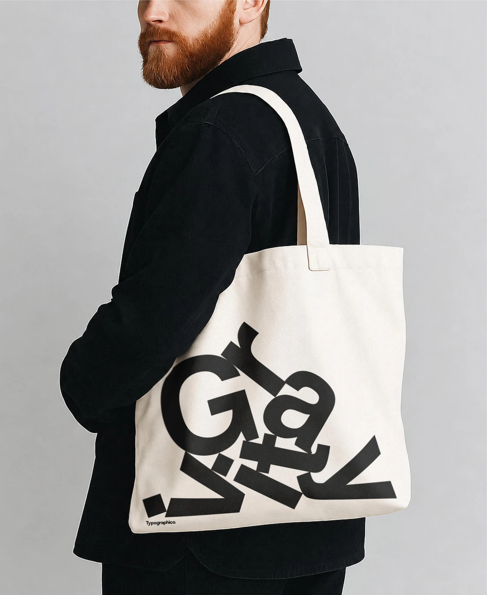 White Gravity tote bag worn over the shoulder by a man in a black jacket.